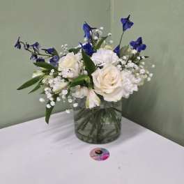White roses and blue flowers in a clear glass vase