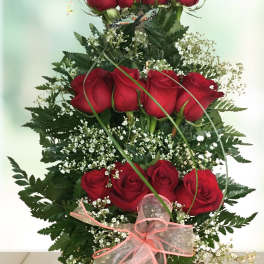 Tiered arrangement of red roses with baby's breath and a pink ribbon bow