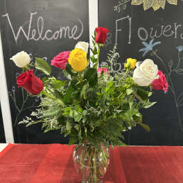 Mixed roses in a clear glass vase with greenery