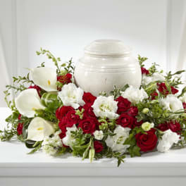 Red roses and white calla lilies arranged around a white urn