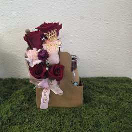 Bouquet of burgundy and pink roses in a gift box with a drink bottle