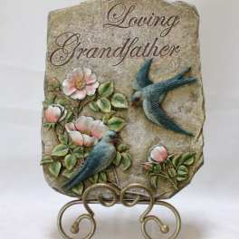 Decorative stone plaque reading "Loving Grandfather" with birds and flowers