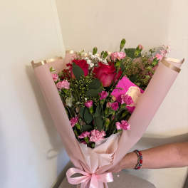 Pink bouquet with red roses and carnations wrapped in blush paper