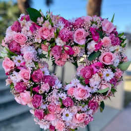 Heart-shaped standing wreath of pink roses, carnations, and daisies on an easel