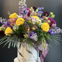 Mixed bouquet in a marble-patterned box with yellow and purple flowers