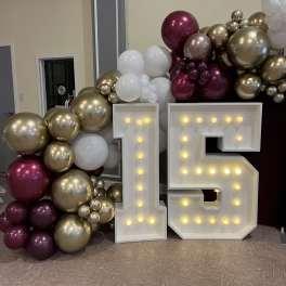 Balloon display with large lit numbers 1 and 5 in front of metallic balloons.