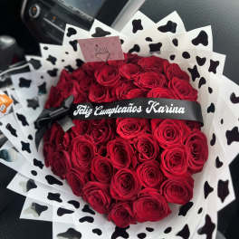 Heart-shaped bouquet of red roses with black-and-white wrap and ribbon