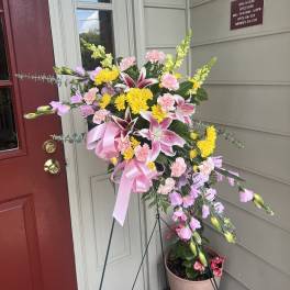 Standing floral spray with pink, yellow, and white flowers on an easel