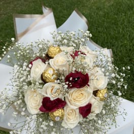 Bouquet of white and red roses with baby’s breath and gold-wrapped chocolates