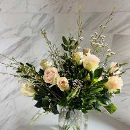 Cream roses arranged in a clear glass vase with airy filler flowers