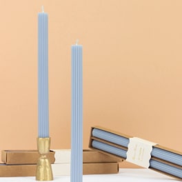 Two light blue ribbed taper candles with boxes and a gold holder