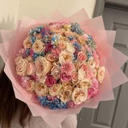 Large bouquet of pink and peach roses with blue filler flowers