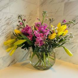 Bouquet of pink and yellow flowers in a clear glass vase
