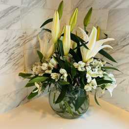 White lilies and alstroemeria arranged in a clear glass vase