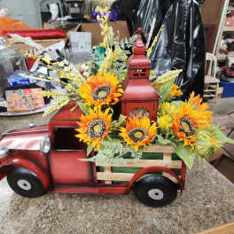 Sunflowers arranged in a red metal truck-shaped container
