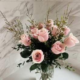 Pink roses arranged in a clear glass vase with airy filler flowers