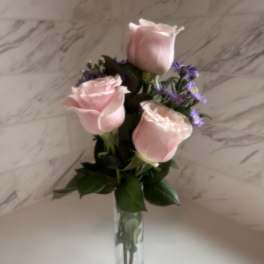 Pink roses with purple filler in a clear glass vase