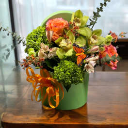 Bouquet of orange and green flowers in a green box with orange ribbon