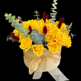 Yellow roses in a round box with a gold ribbon