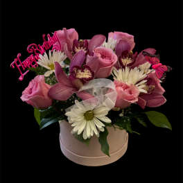 Pink and white flower arrangement in a round box with a birthday topper
