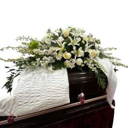 White floral spray on top of a dark casket