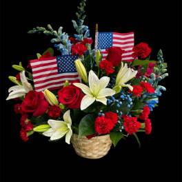 Basket arrangement of red carnations, white lilies, and small American flags