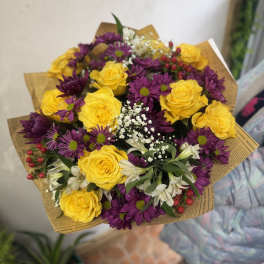 Bouquet of yellow roses and purple daisies with white filler flowers