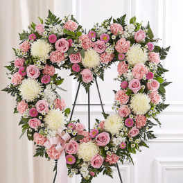Heart-shaped floral wreath with pink and white flowers on a stand
