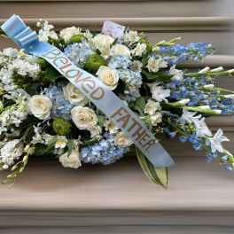 Sympathy spray of white and blue flowers with a "Beloved Father" ribbon