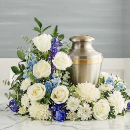 White roses and blue-purple flowers arranged around a metal urn