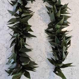 Two dark green leaf garlands arranged in a U shape on a light surface.