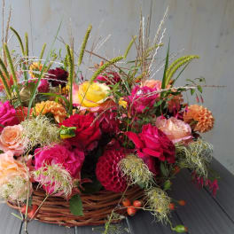 Basket of colorful roses and dahlias with tall grasses
