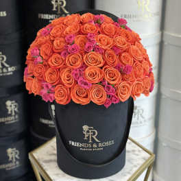 Round bouquet of orange and pink roses in a black hat box