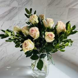 Pale peach roses arranged in a clear glass vase