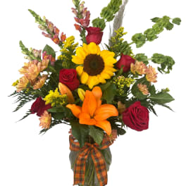 Sunflower and red rose bouquet in a glass vase with an orange ribbon