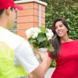 Person handing a bouquet of white flowers to a woman in a red shirt