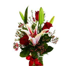 Red roses and pink lilies in a glass vase with a red ribbon
