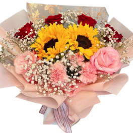 Bouquet of sunflowers, red roses, pink roses, and carnations wrapped in blush paper