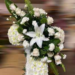 Tall white sympathy spray with roses, lilies, carnations, and cushion of chrysanthemums accented with ribbon