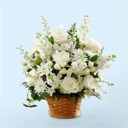 All-white roses, mums, and stock arranged in a woven basket