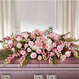 Pink and white casket spray with lilies, roses, carnations and trailing blooms on a closed casket.