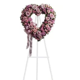 Heart-shaped pink rose wreath on a standing easel with ribbon