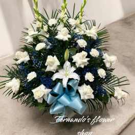 Fan-shaped white roses, carnations, and lilies with blue accents and a light blue bow.