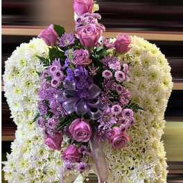 Sympathy pillow of white mums with central spray of lavender roses and daisies, finished with a purple ribbon bow.