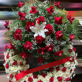 Large red and white funeral wreath with roses, lilies, and carnations on a standing frame