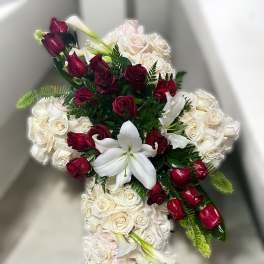 Cross-shaped arrangement of white roses with red roses and white lilies in the center