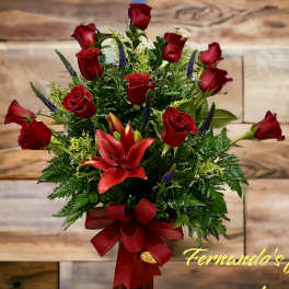 Tall arrangement of red roses and red lilies with a large red bow