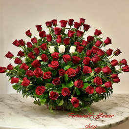 Large fan-shaped arrangement of red roses with a cluster of white roses in a low basket.