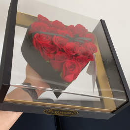 Heart-shaped box of red roses under a clear lid