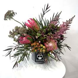 Pink protea arrangement in a gray container